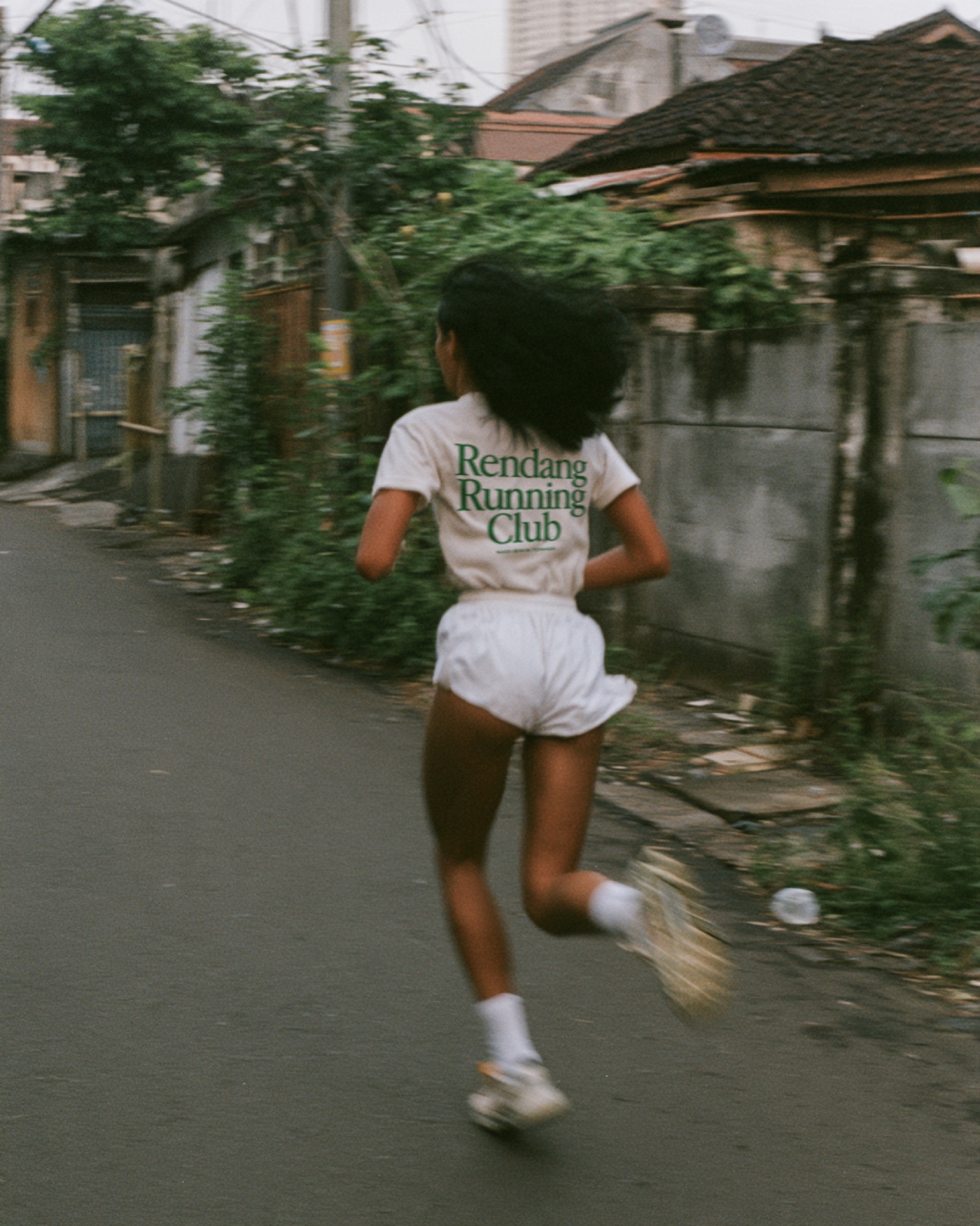 A runner in the Rendang Running Club tee on a neighborhood street